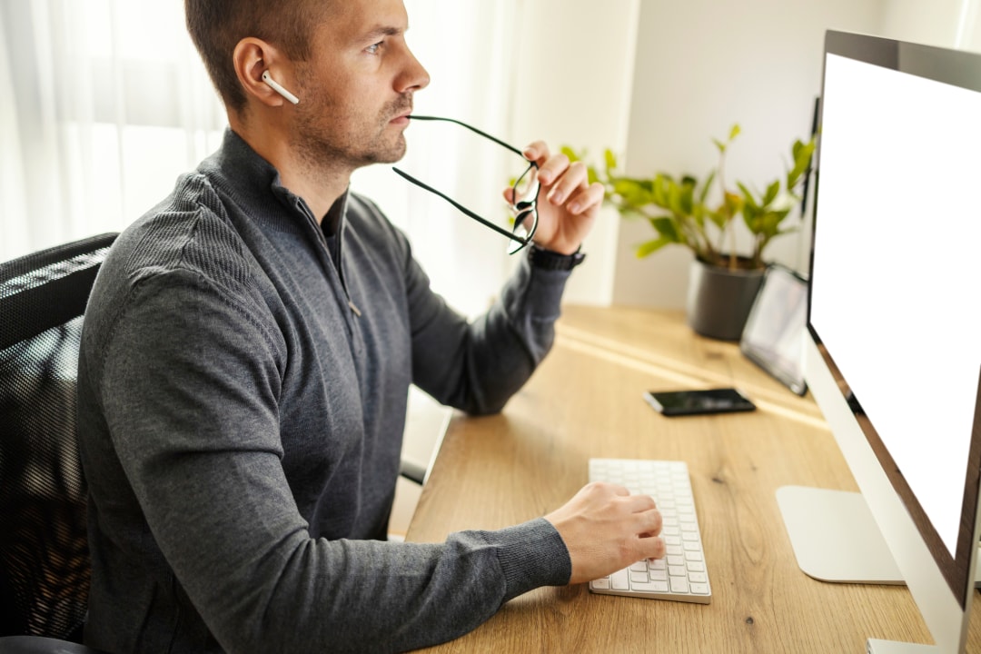A man sits at a desk concentrating while he works on his computer.